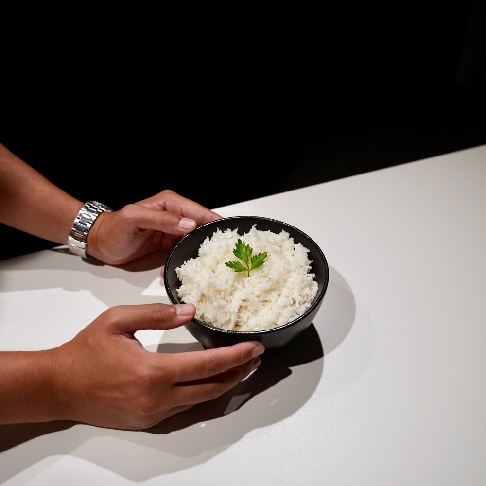 Two hands holding a black bowl of prepared Cut Kitchen rice beneath the words Uncompromised taste and texture