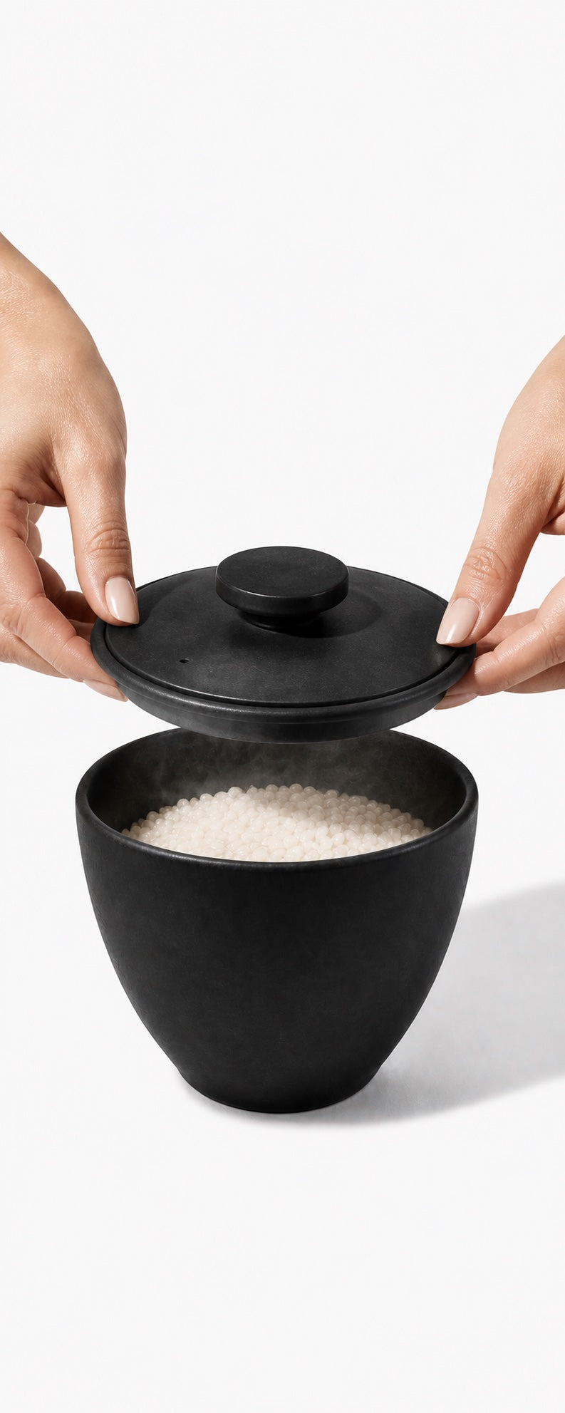 Two hands placing a ceramic lid over the bowl of rice