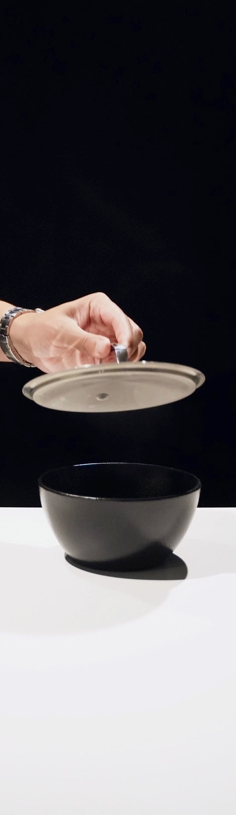 Two hands placing a ceramic lid over the bowl of rice