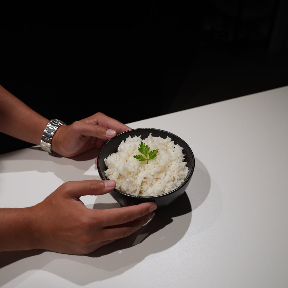 Two hands holding a black bowl of prepared Cut Kitchen rice beneath the words Uncompromised taste and texture