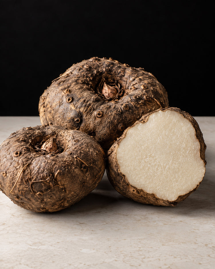 Whole and cut konjac tubers on a pale stone surface