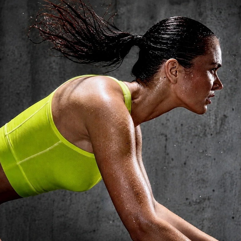Athlete in a lime training top leaning forward against a dark concrete background